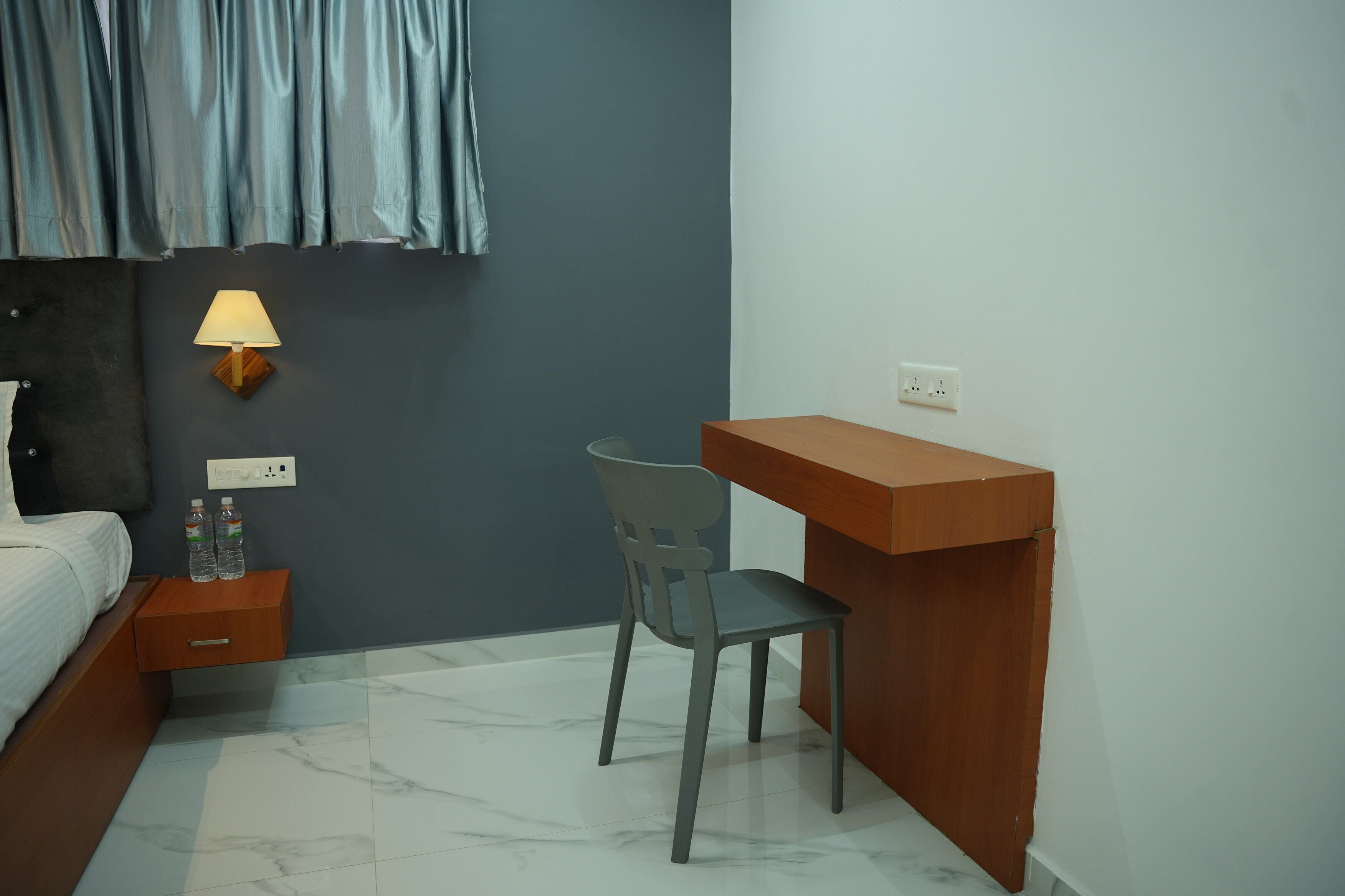 Un dormitorio con cama, una mesita de noche con lámpara, una silla y un escritorio.