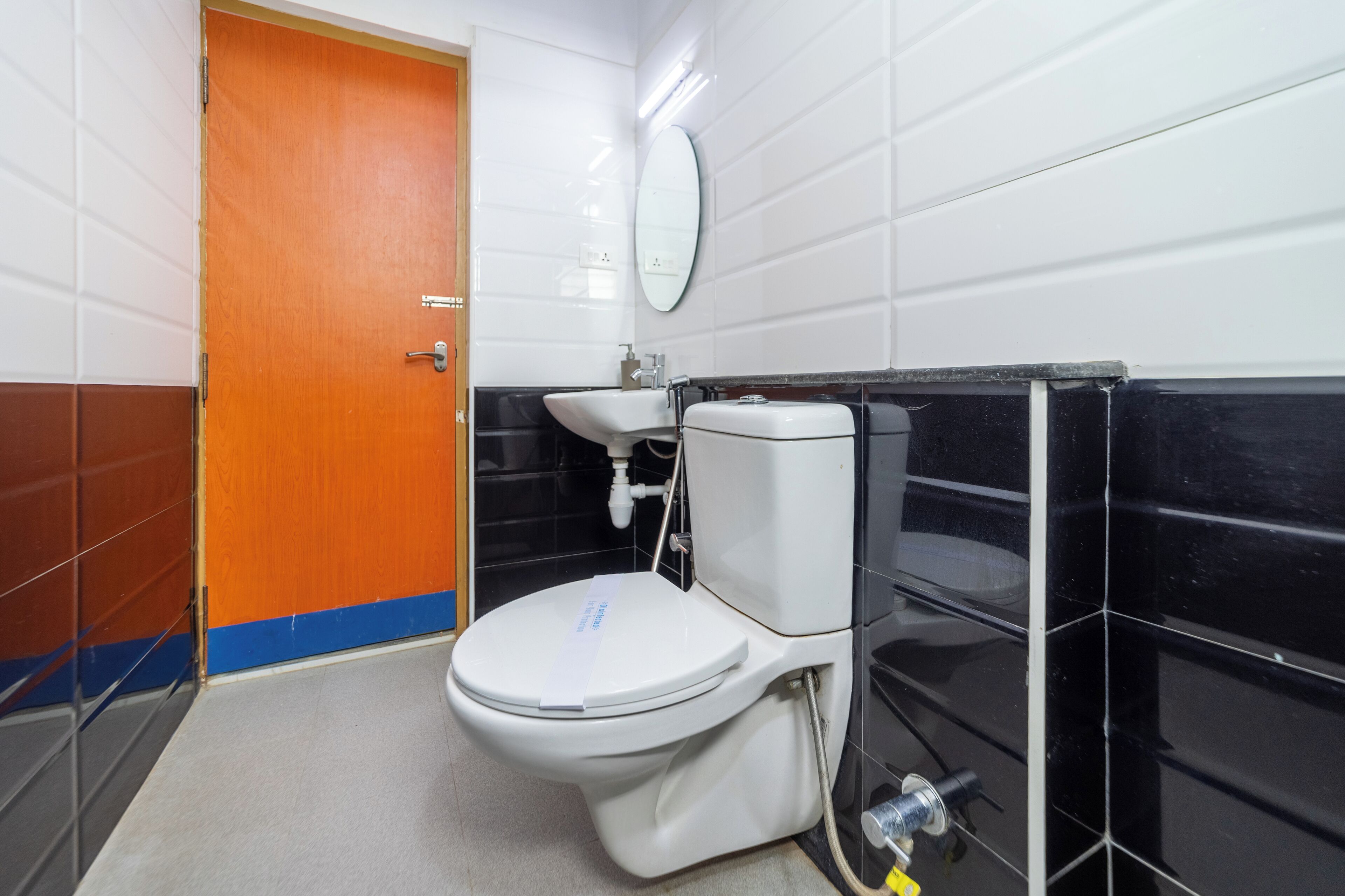 Un baño con inodoro blanco, lavabo y espejo.
