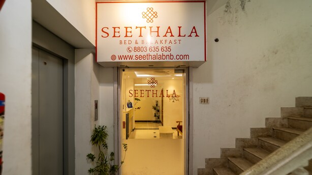 Entrada de hotel com uma placa indicando "SEETHALA BED & BREAKFAST" e uma escadaria que leva ao interior.