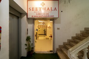 A hotel entrance with a sign reading "SEETHALA BED & BREAKFAST" and a staircase leading inside. - Seethala Bed & Breakfast (Puducherry)
