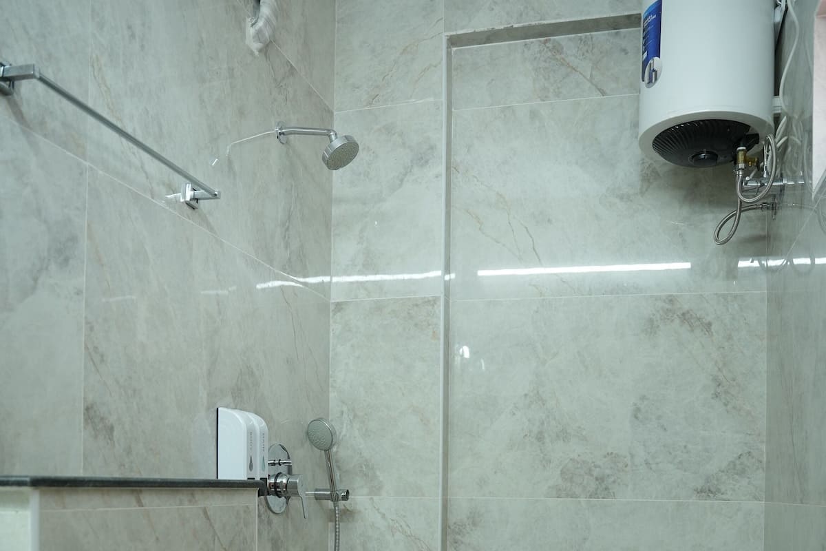 A bathroom with a toilet, a shower, and a built-in heater.