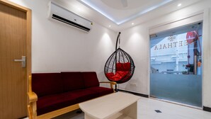 Um interior moderno com um sofá vermelho, uma cadeira suspensa com almofada vermelha, uma mesa de madeira e uma porta de vidro com vista para o exterior.