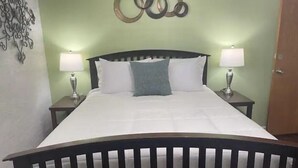 A bed with white bedding, two bedside lamps, and a decorative wall piece above the bed.