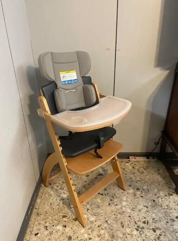 A high chair with a tray table in a room with a tiled floor.