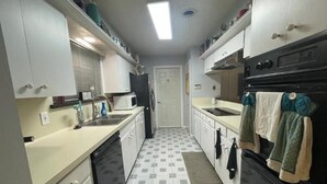 A compact kitchen with white cabinets, a black stove, and a microwave.