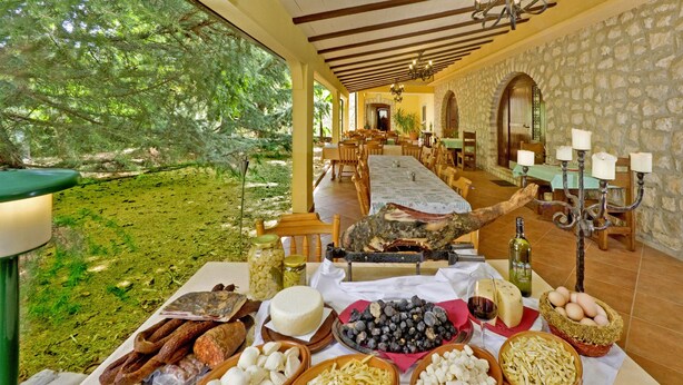 Un comedor con una mesa dispuesta para una comida, con varios quesos, embutidos y frutas.