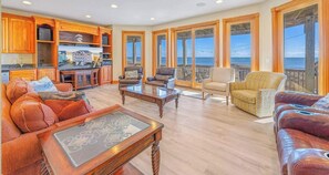 A spacious living area with a kitchen, dining area, and a balcony with a view of the ocean.