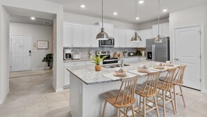Eine moderne Küche mit weißen Schränken, Granit-Arbeitsplatten, Edelstahlgeräten und Holzbarhocker.