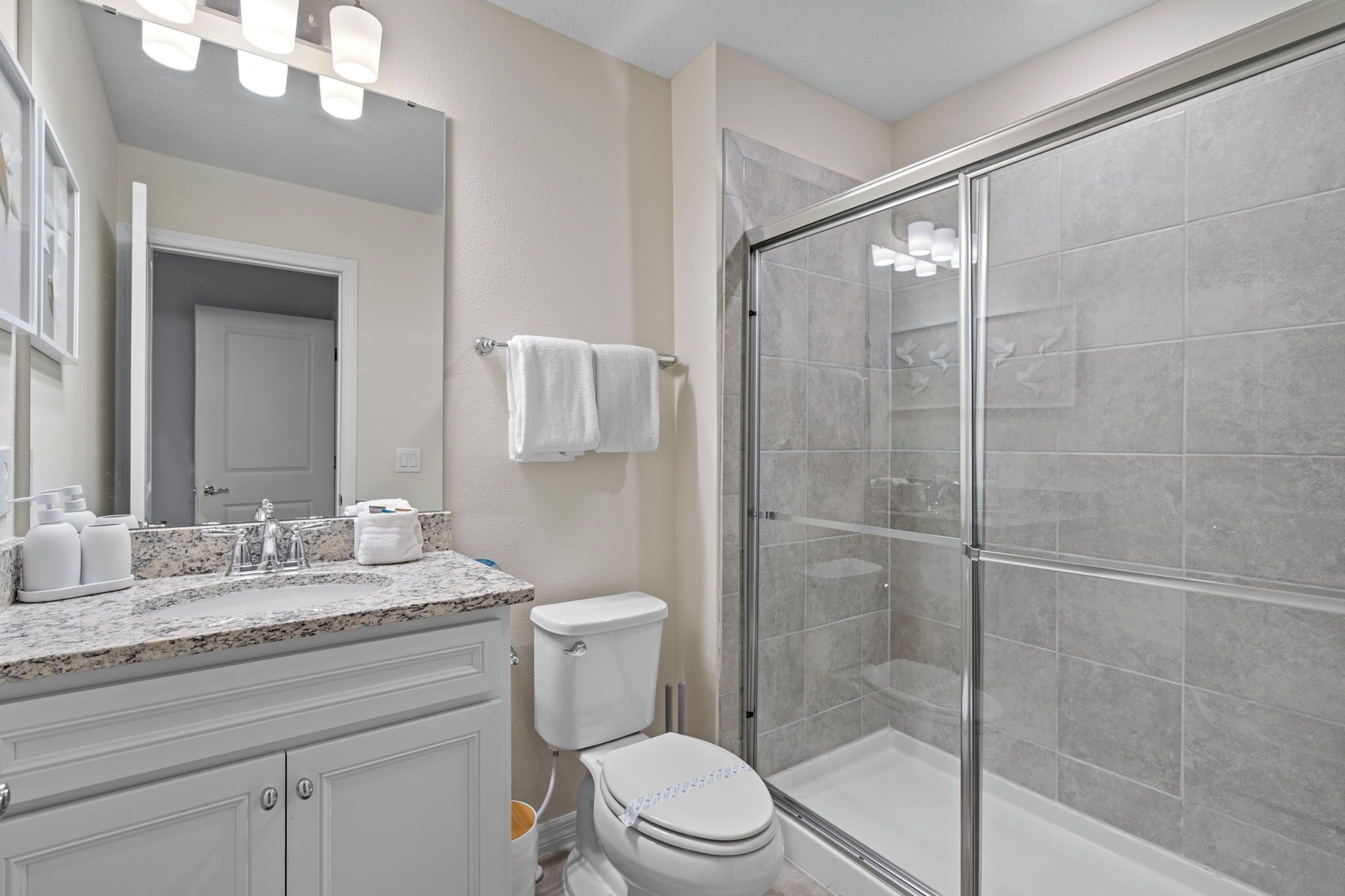 A modern bathroom with a glass-enclosed shower, a white toilet, and a marble countertop with a sink.