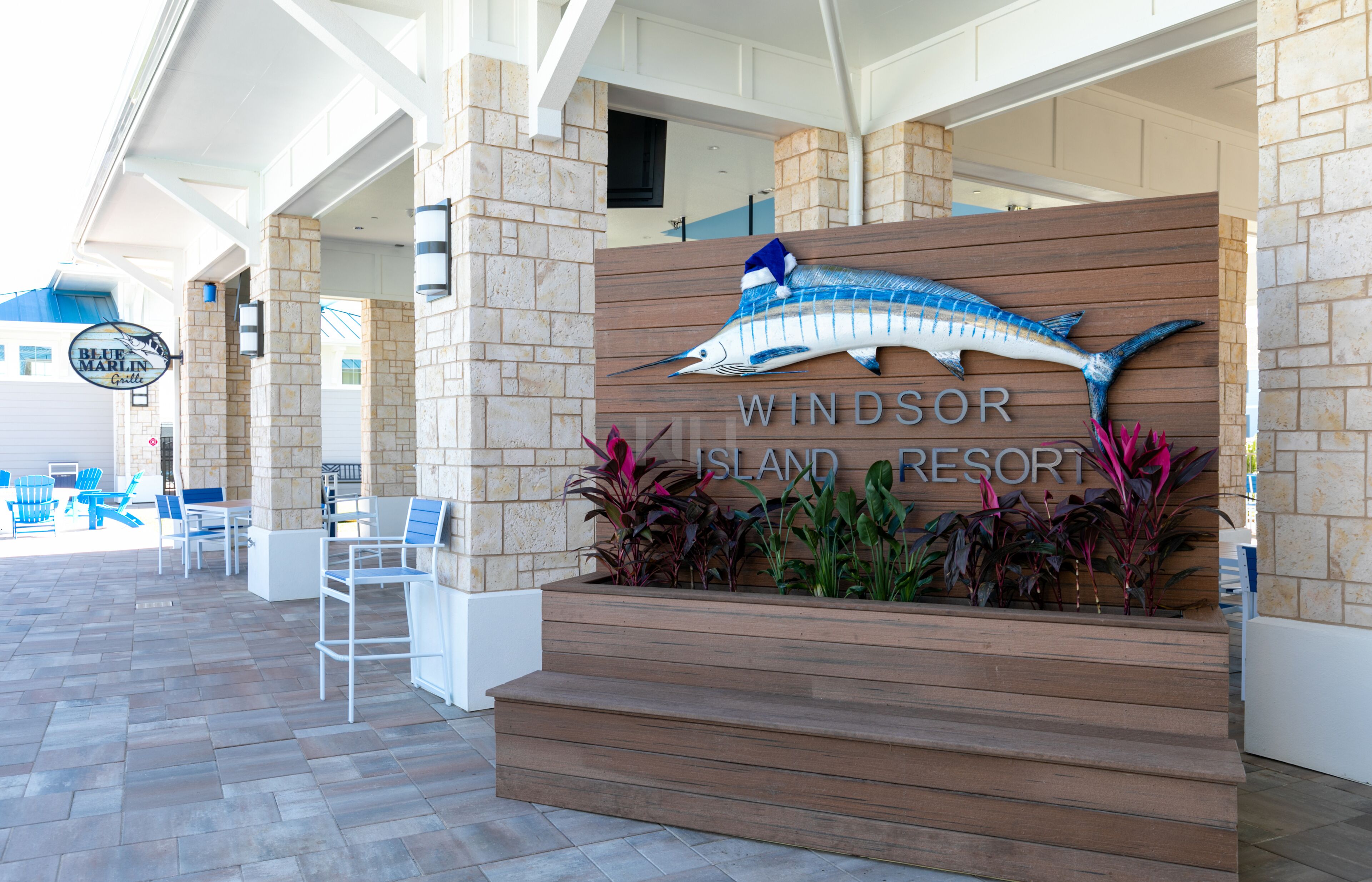 Ingången till Windsor Island Resort, med en skylt som förest äller en blå marlin, utomhusmöbler och en fasad av sten.