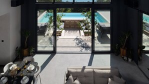 A modern interior with a large window overlooking a pool and a view of the sea.