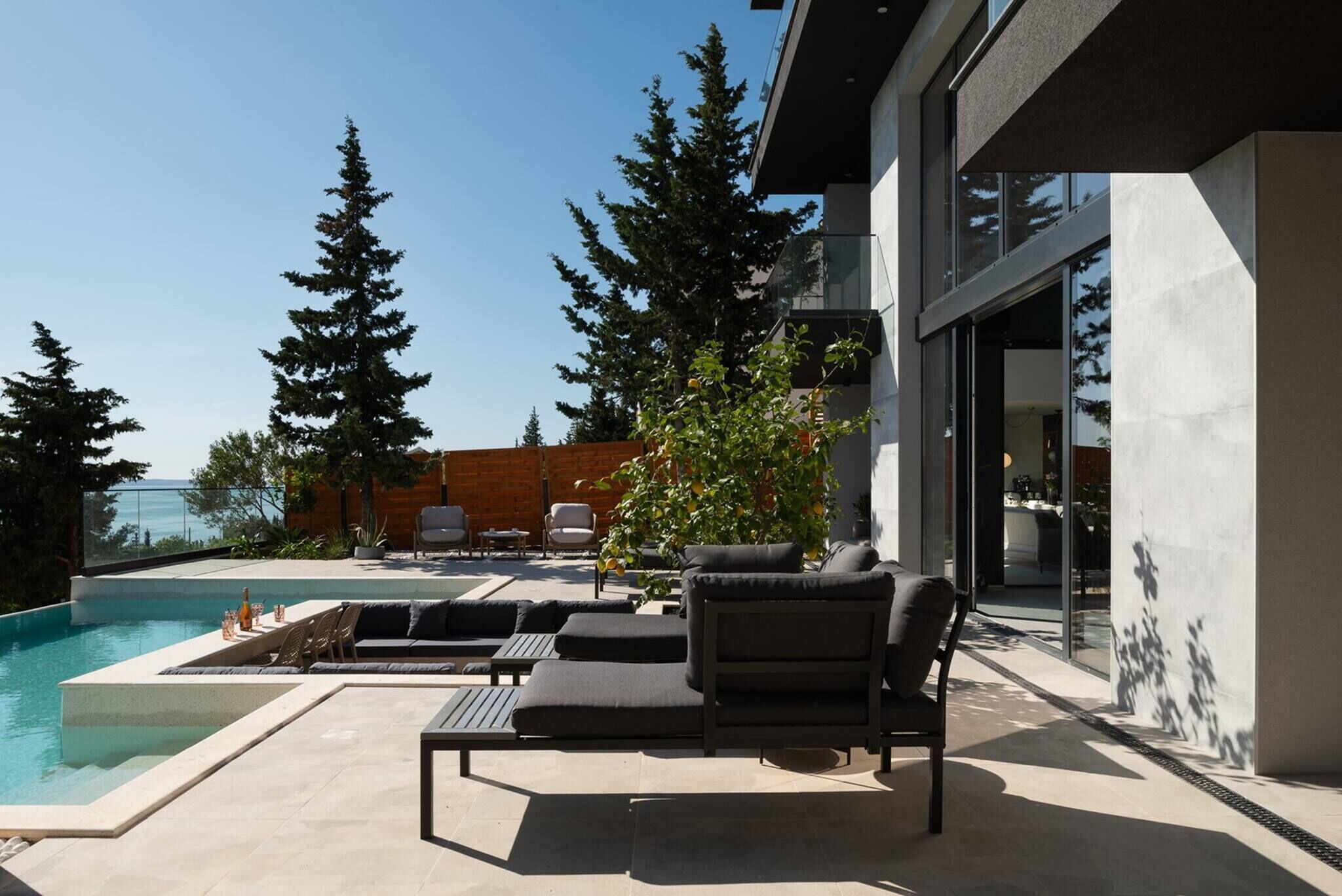 A modern outdoor pool area with lounge chairs and a wooden deck.
