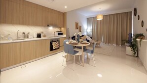 A modern kitchen with wooden cabinets, a marble countertop, and a dining area with a round table and blue chairs. - Luxury StayCation - Beachfront Apartment With Fantastic Palm Views  (Dubai)