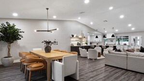 A modern living room with a dining area, a kitchen, and a large potted plant. - Scottsdale Clubhouse | Pool, Spa & Golf Simulator (Scottsdale)