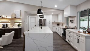 A modern kitchen with white cabinetry, a marble island, and a pendant light. - Scottsdale Clubhouse | Pool, Spa & Golf Simulator (Scottsdale)