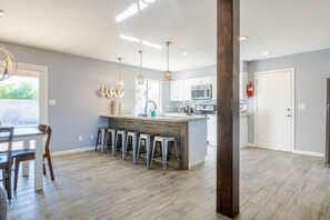 A spacious kitchen with a central island, bar stools, pendant lighting, and a view to the outdoors. - Kierland Jewel | Pool+Game Room+ Putt+Fire Pit! (Scottsdale)