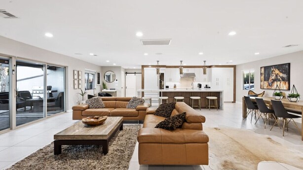 A modern living room with a sofa set, a coffee table, and a dining area with a wooden table and chairs.