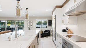 A modern kitchen with a large island, stainless steel appliances, and pendant lighting.