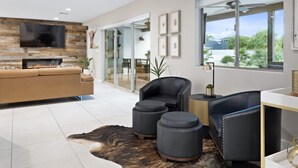 A modern living room with a fireplace, leather furniture, and a large window offering a view of the outdoors.