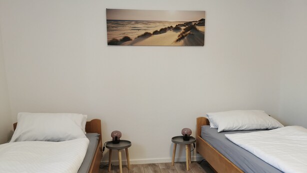 A bedroom with two beds, a small table, and a wall-mounted picture. - P2 Schönes Apartment in Fuldatal (Fuldatal)