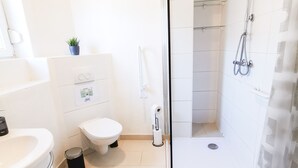 A modern bathroom with a glass shower enclosure, a toilet, and a sink. - P2 Schönes Apartment in Fuldatal (Fuldatal)
