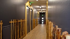 A hallway with wooden partitions and doors, leading to a room with a visible emergency exit sign. - Le Vent du Large (Saint-Gilles-Croix-de-Vie)