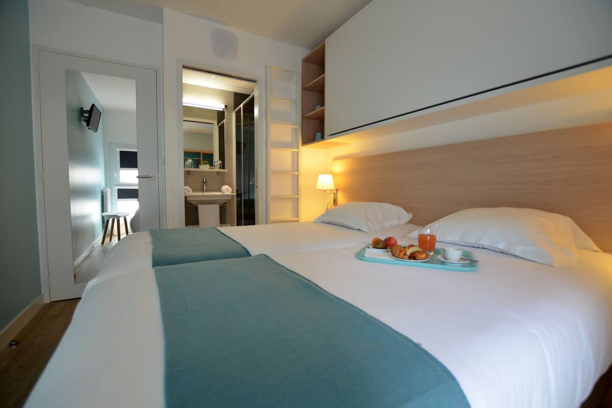 Una habitación de hotel con dos camas, baño y kitchenette.