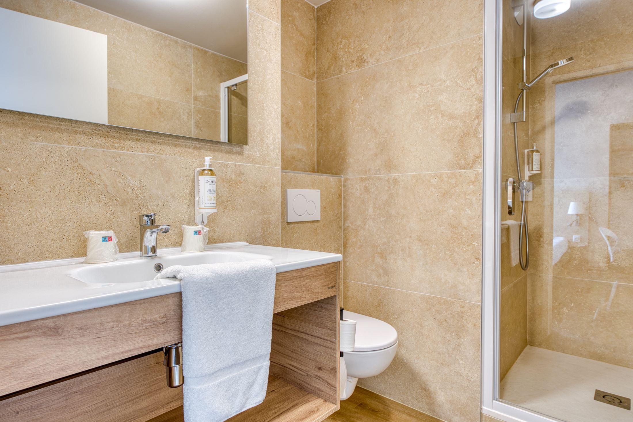A bathroom with a sink, mirror, toilet, and shower.