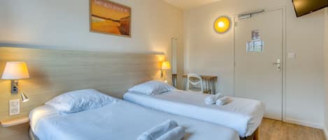 Habitación de hotel con dos camas, un televisor, un cartel y un escritorio con una silla.