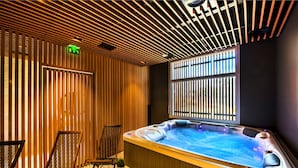 A spa area with a hot tub, wooden slats, and two chairs. - Le Vent du Large (Saint-Gilles-Croix-de-Vie)