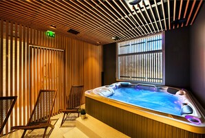 Un espace bien-être comprenant un jacuzzi, des lattes en bois et deux fauteuils.