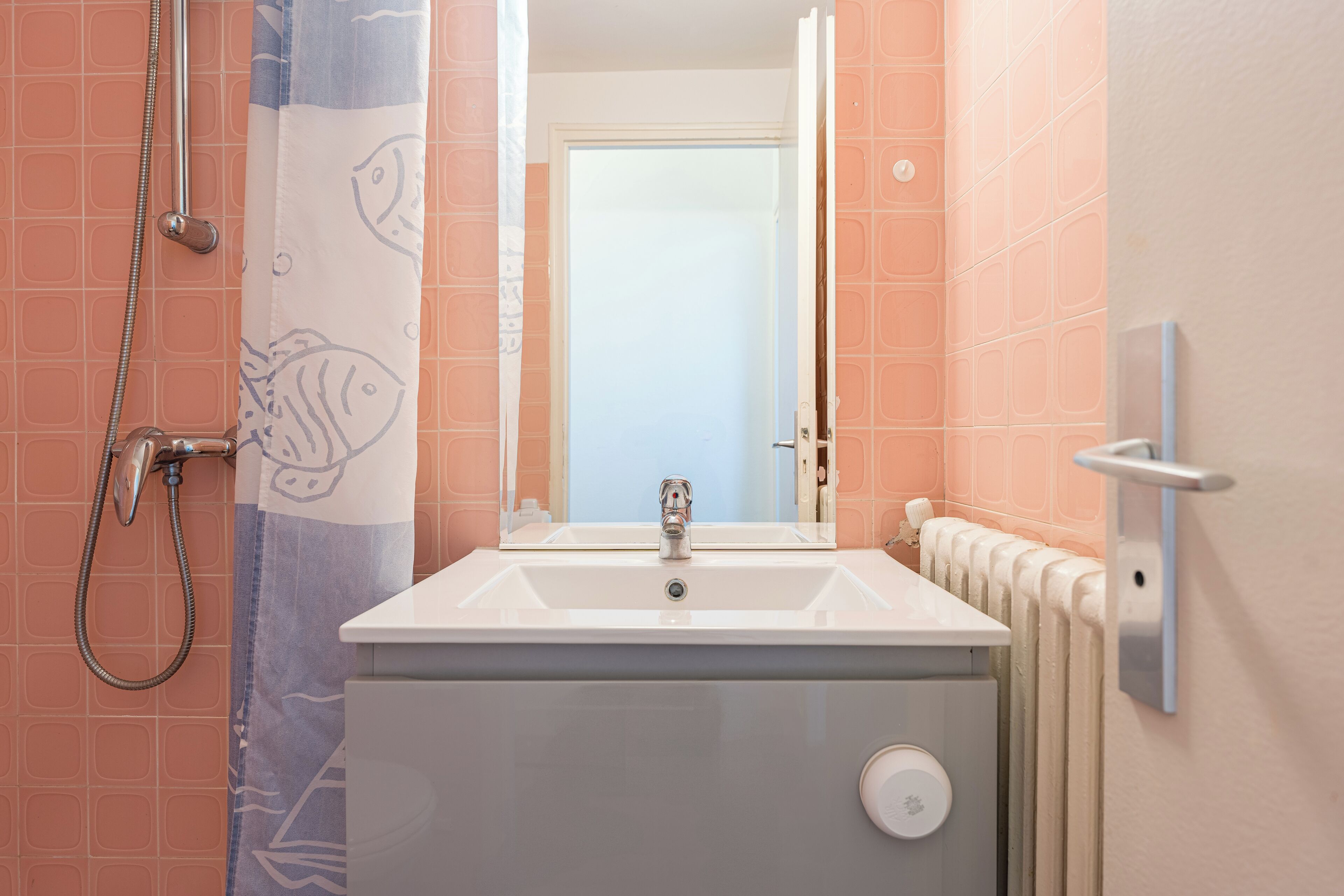 Ein Badezimmer mit einem weißen Waschbecken, einer Dusche mit blauer Duschvorhang und einer sichtbaren Toilette.