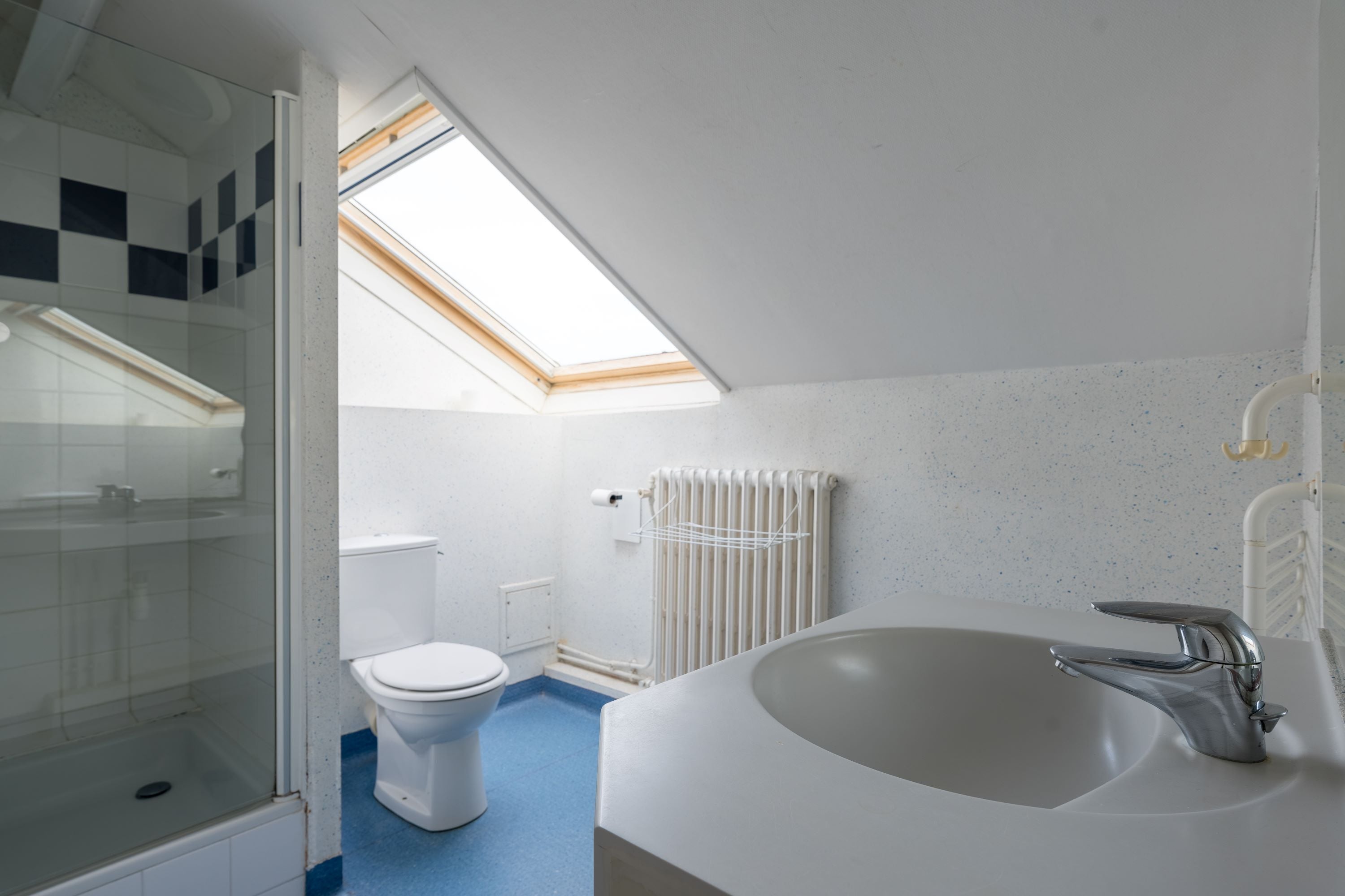 A modern bathroom with a skylight, a bathtub, and a shower enclosure.