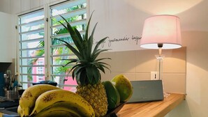A kitchen counter with a fruit bowl containing bananas, a pineapple, and a guava. There is a Philips radio and a lamp on the counter. - Villas "les Saintes" Pour 4 à 5 Personnes à 50 m de la Plage au Calme (Saint-François)