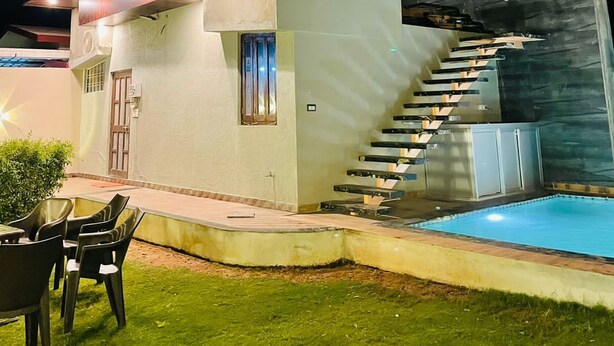 Ein modernes Mehrfamilienhaus mit sichtbarer Treppe zum Obergeschoss, einem Schwimmbad und Sitzgelegenheiten im Freien.