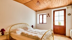 A bedroom with a bed, a nightstand, a window, and a door. - Town centre - House for 4 with beautiful courtyard (Noirmoutier-en-l´Ile)