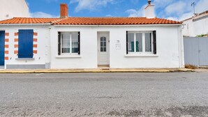A white building with a red-tiled roof, two windows, and a door. - Town centre - House for 4 with beautiful courtyard (Noirmoutier-en-l´Ile)