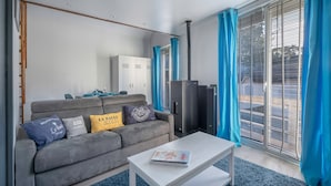 A modern living room with a grey sofa, a white coffee table, and a large window with blue curtains. - Flat for 4 - 300m from the beach in La Baule (La Baule-Escoublac)
