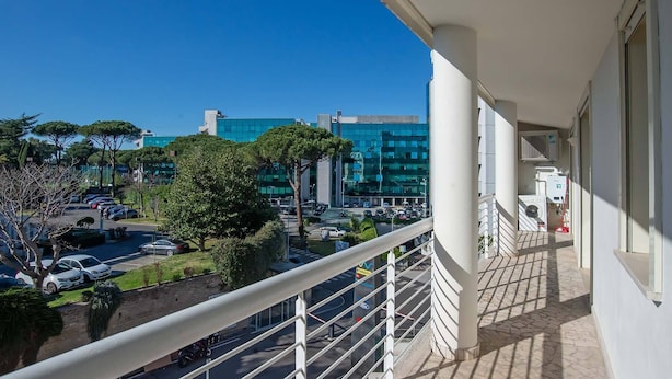 A balcony with a view of a parking lot and buildings.