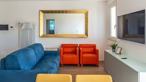 A modern living room with a blue sofa, two orange chairs, and a yellow table.