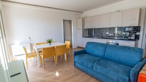 A compact living space with a dining area, a kitchenette, and a blue sofa.