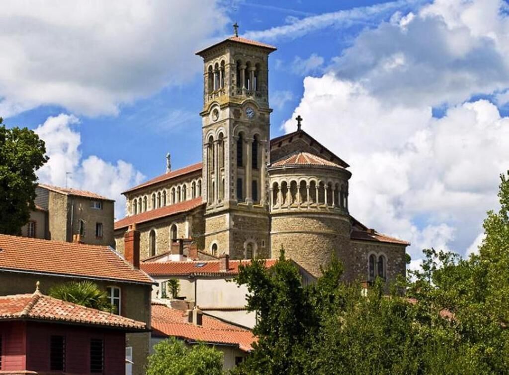 Un edificio histórico con una torre destacada y una cúpula, rodeado de árboles y otros edificios.