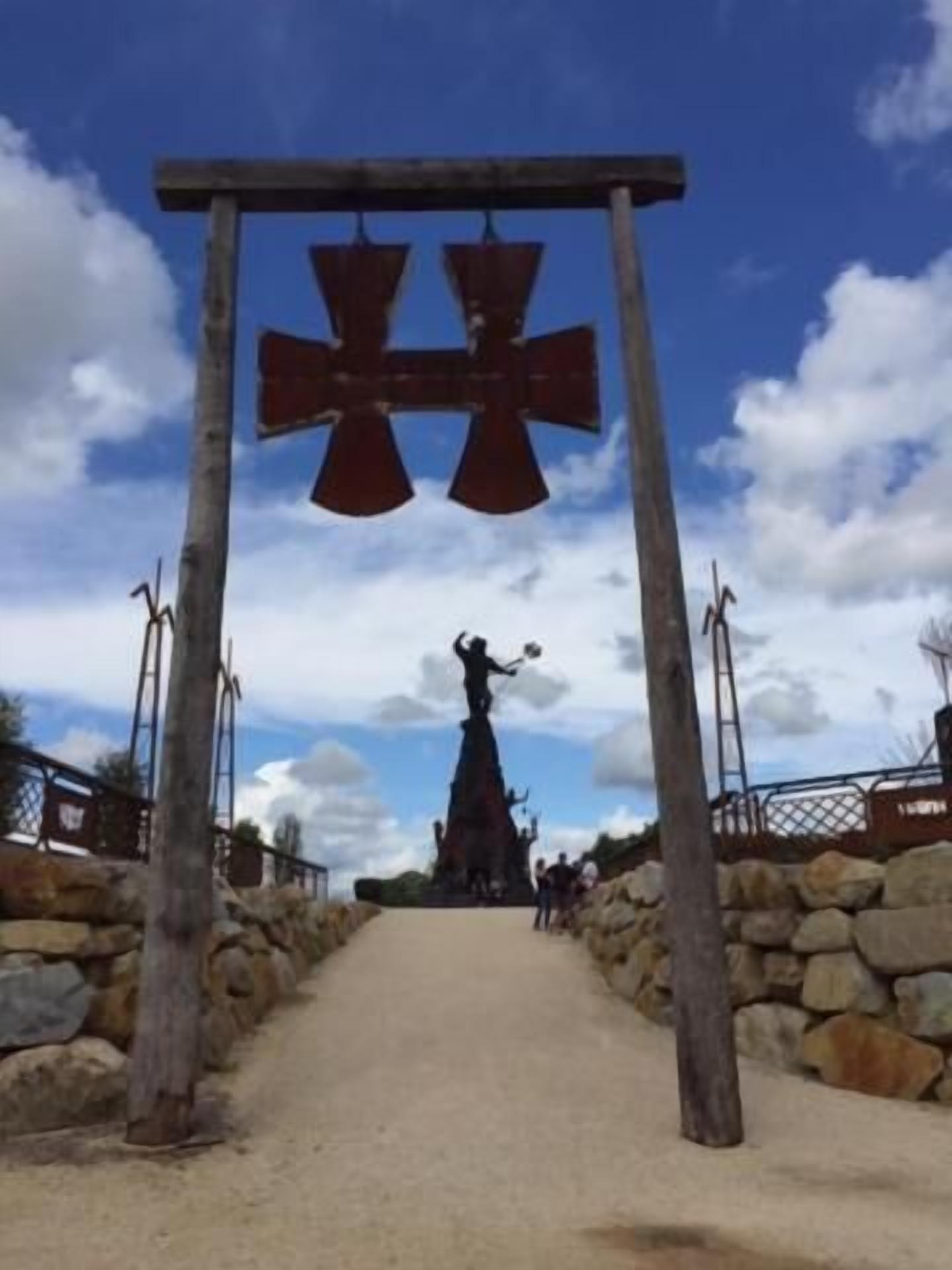 A pathway leading to a statue under a wooden archway.