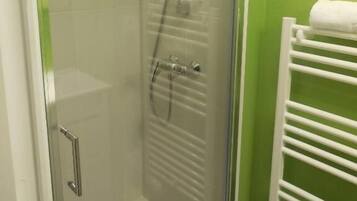 Ducha con cerramiento de vidrio, cabezal de ducha de mano y grifo empotrado.