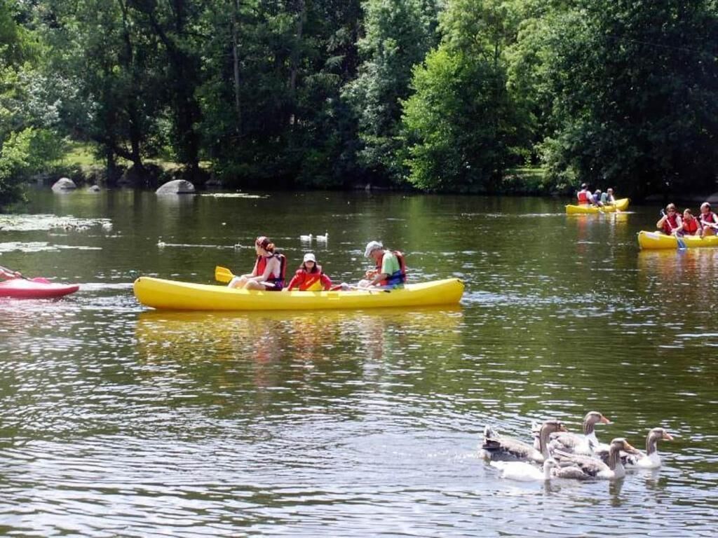 People kayaking on a calm river surrounded by dense trees.