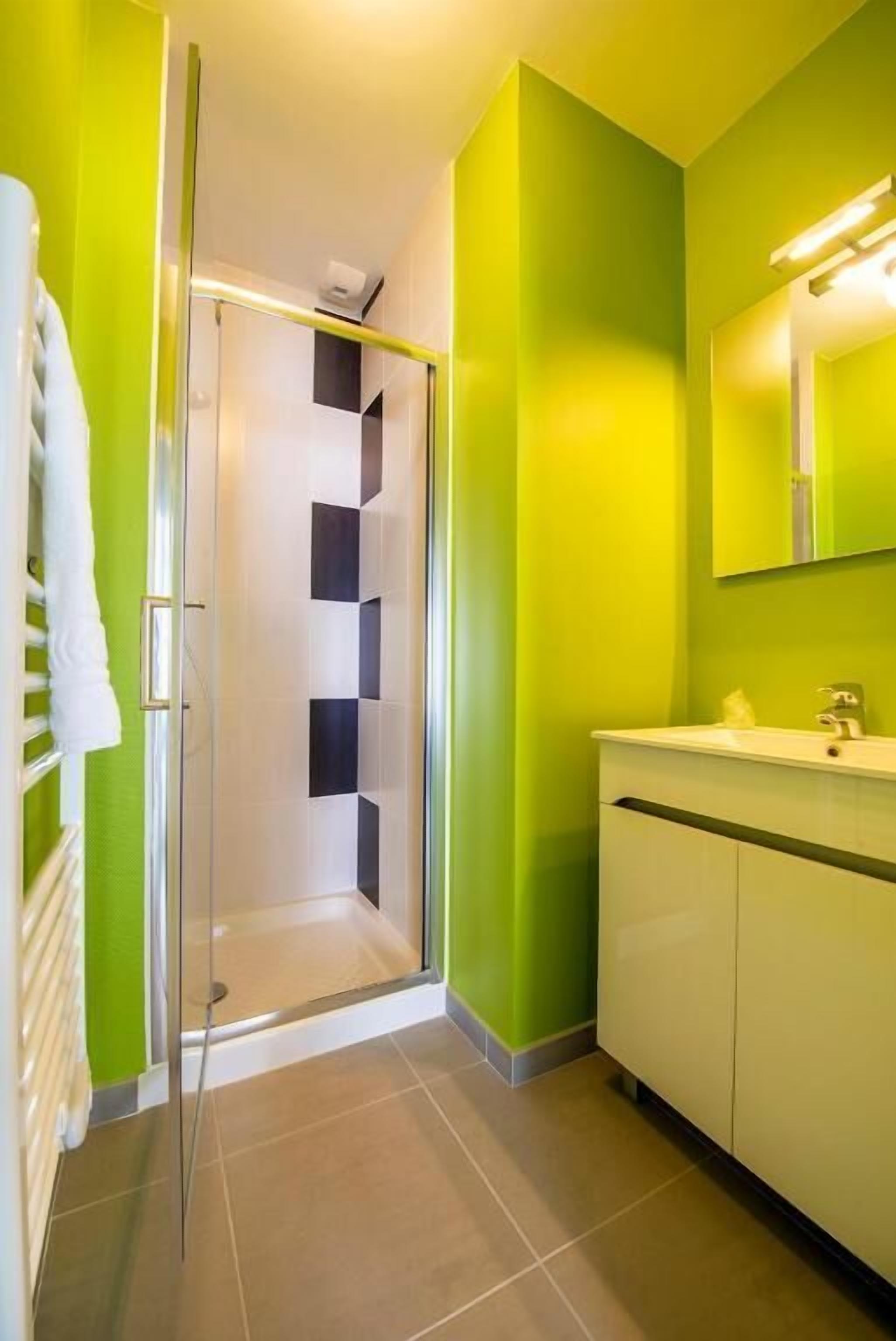 Une salle de bain avec une douche à parois de verre, un lavabo blanc et un miroir au-dessus.