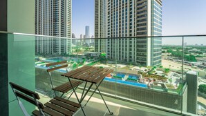 Varanda com vista para edifícios altos e área de piscina.