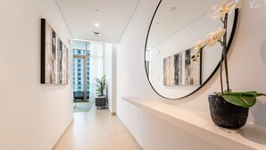 Um corredor moderno com obras de arte nas paredes, uma orquídea em vaso e vista para um edifício através de uma porta de vidro.