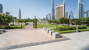Uma praça urbana moderna com calçada pavimentada, bancos e áreas verdes.