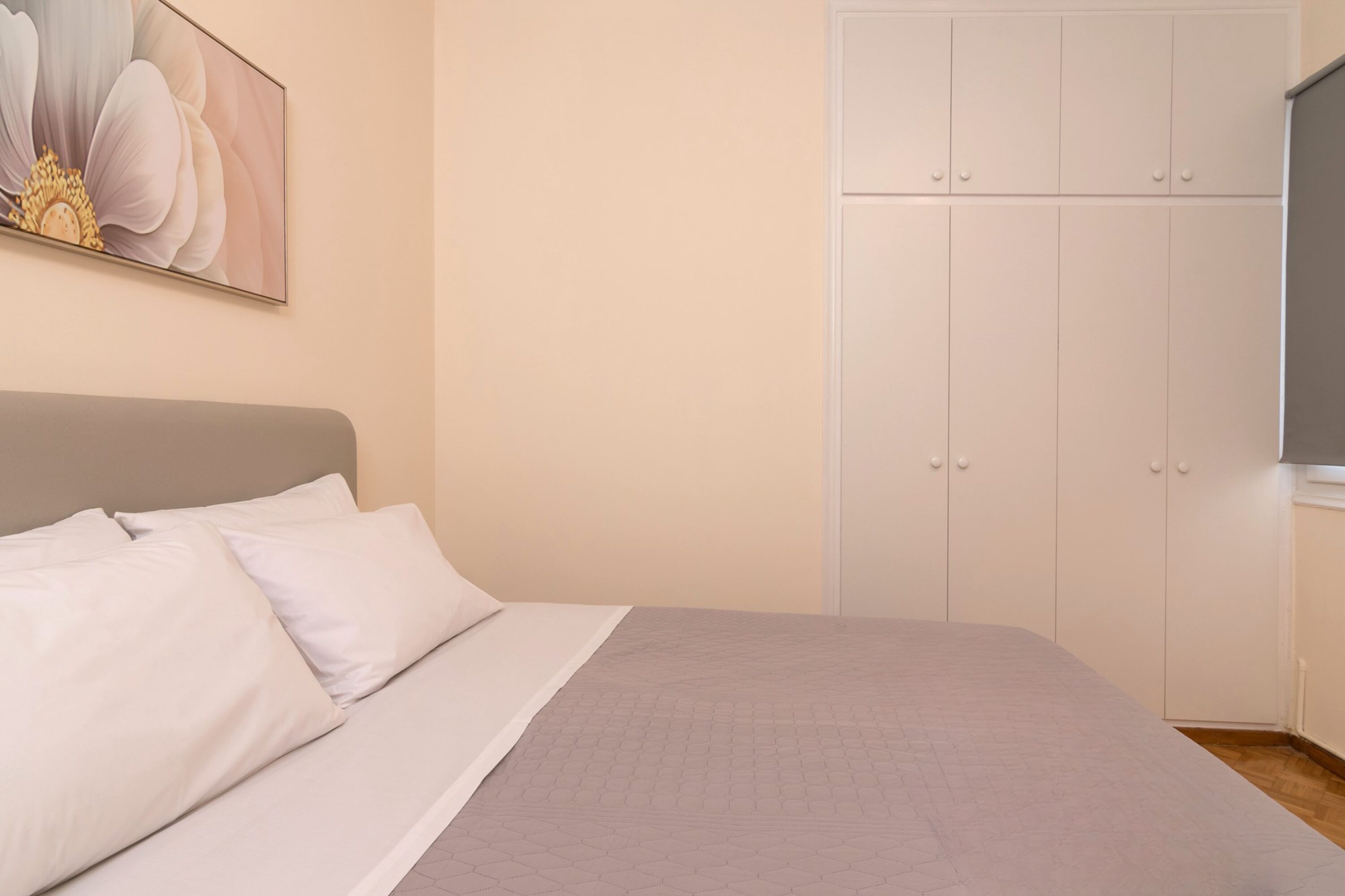 A bedroom with a bed, a wardrobe, and a painting on the wall.